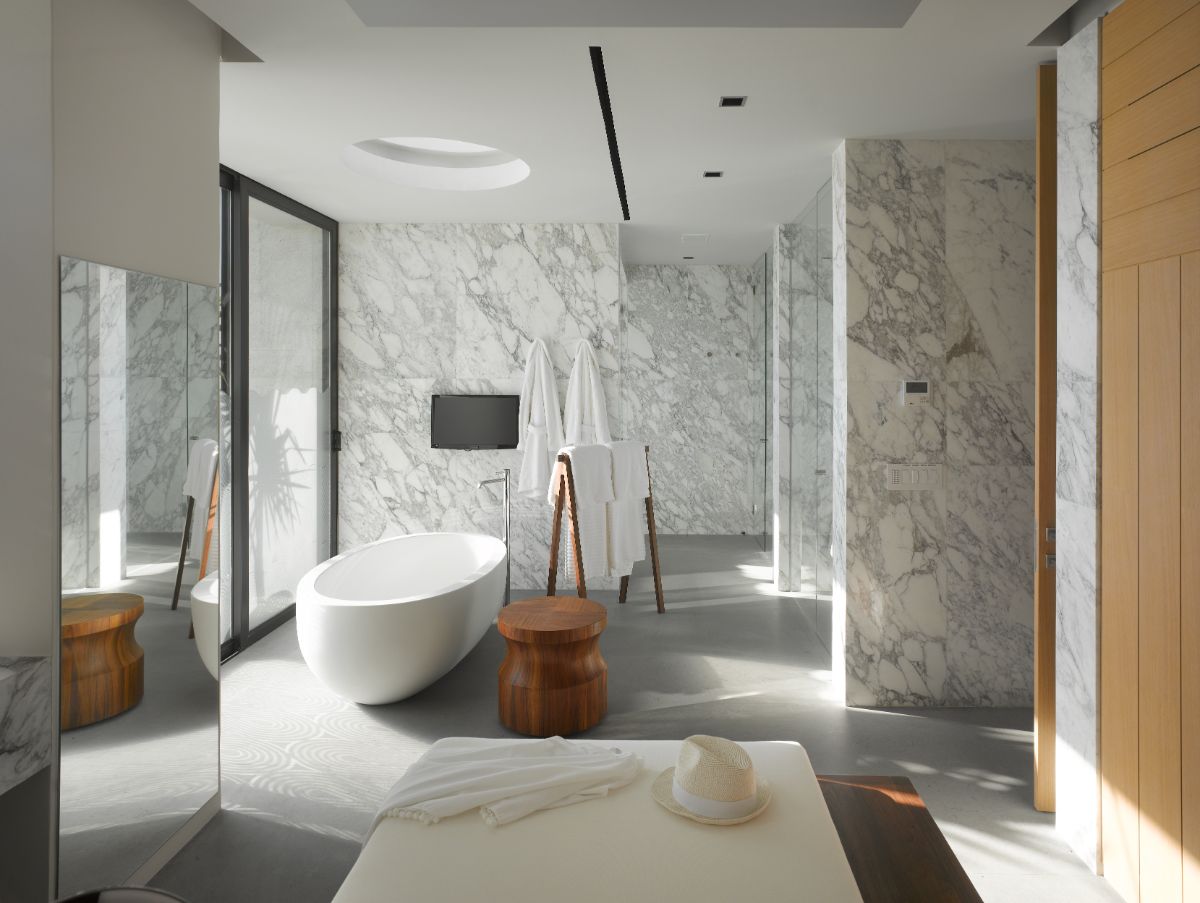 The bathroom has a freestanding tub and a floor-to-ceiling window that lets in natural light. The marble wall adds a touch of luxury.