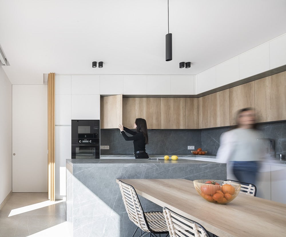 The kitchen features a marble island integrated with a wooden eating bar.