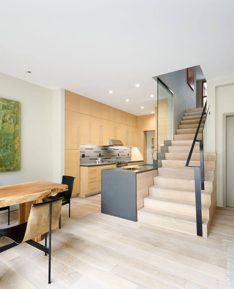 A street house unit has clean-lined kitchen fittings and a dining room. The kitchen island was framed by the light wood staircase.