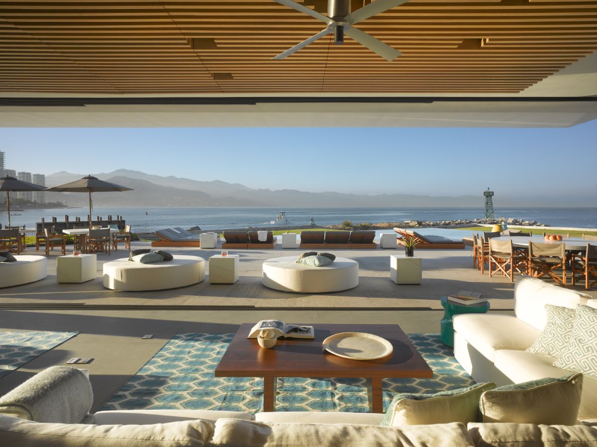 A multifunctional outdoor space within the house featuring living, dining, and lounge areas that open to the view.