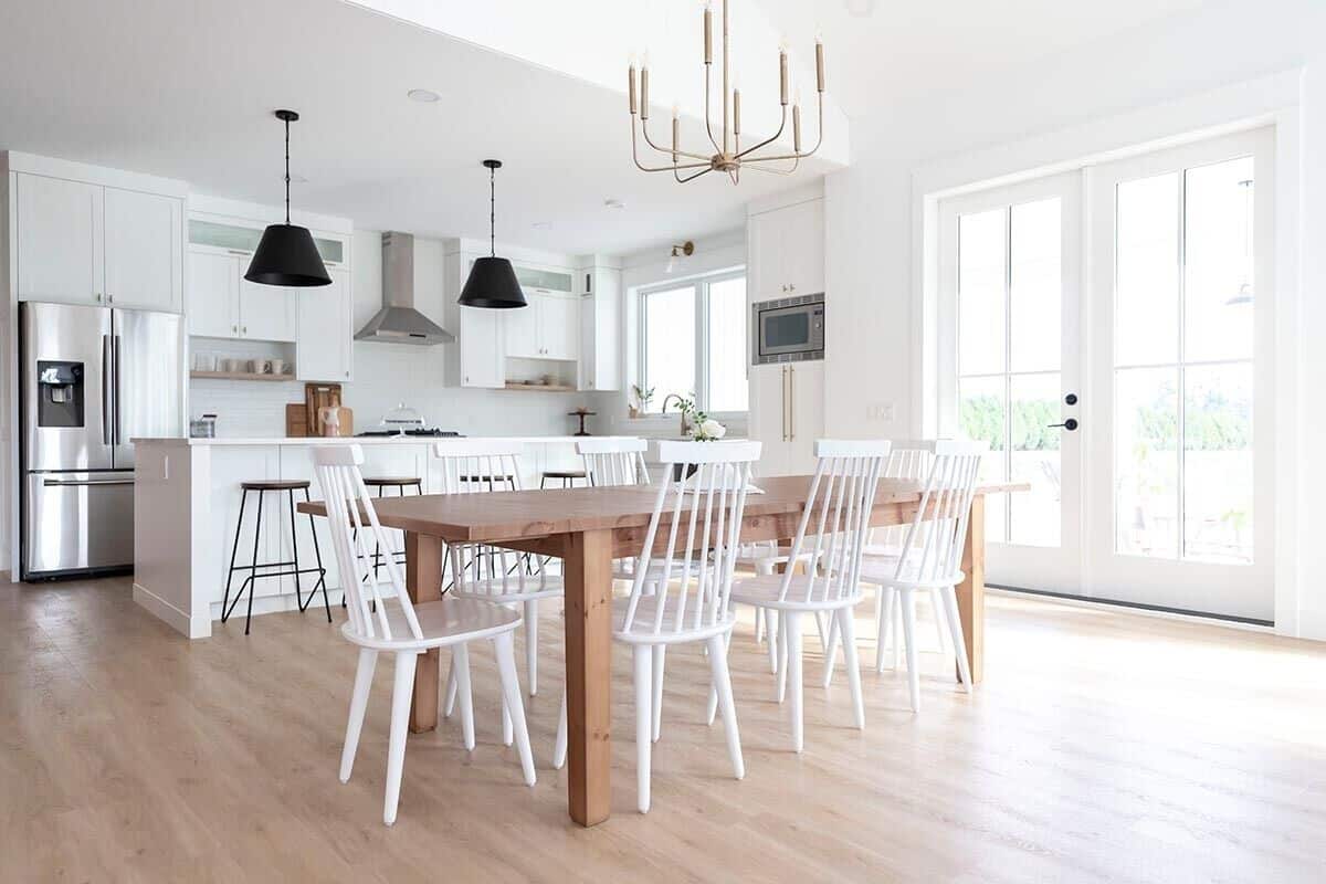 The dining area features a rustic wooden table surrounded by white chairs.