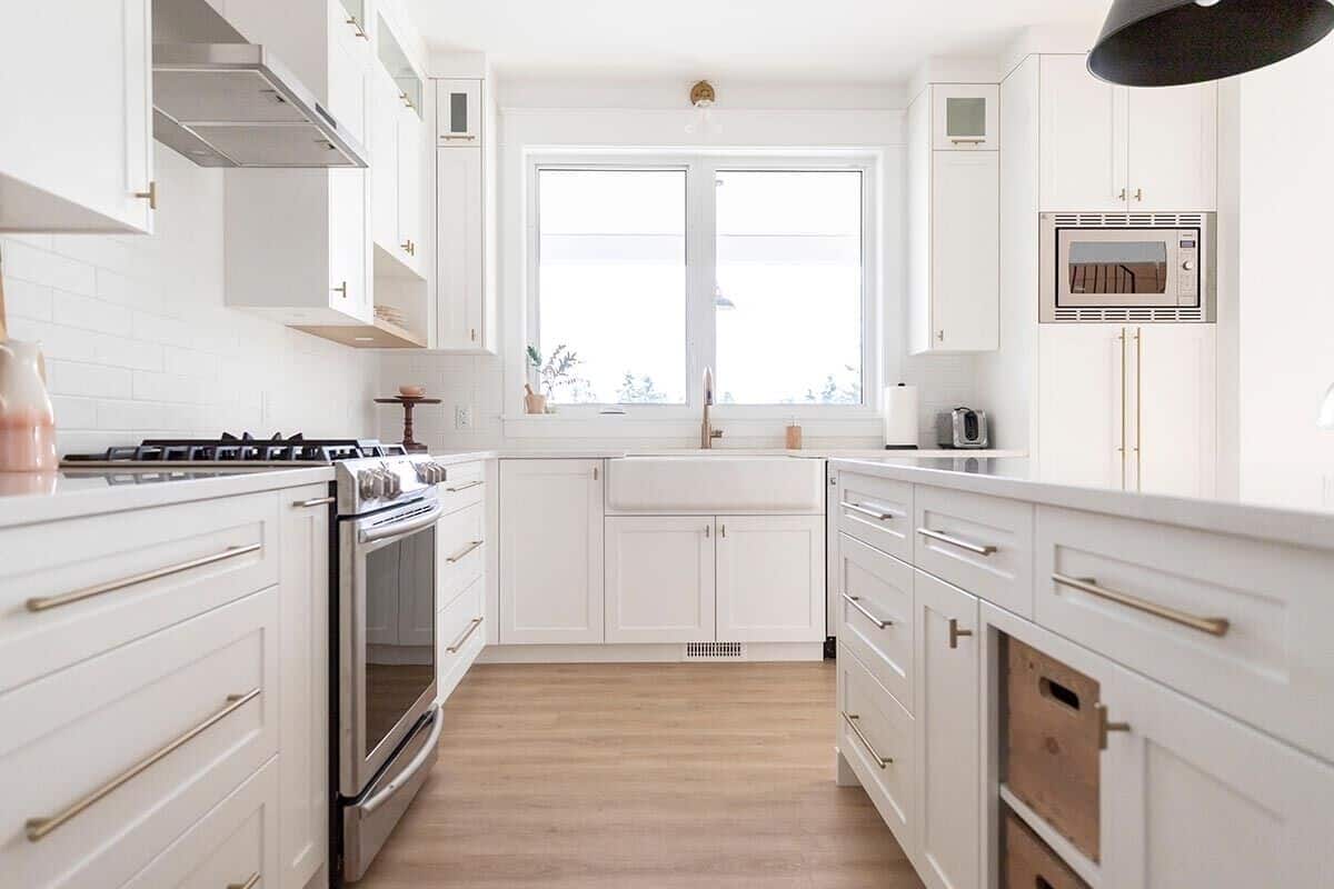 The kitchen is equipped with stainless steel appliances, white cabinets, a farmhouse sink, and a prep island.