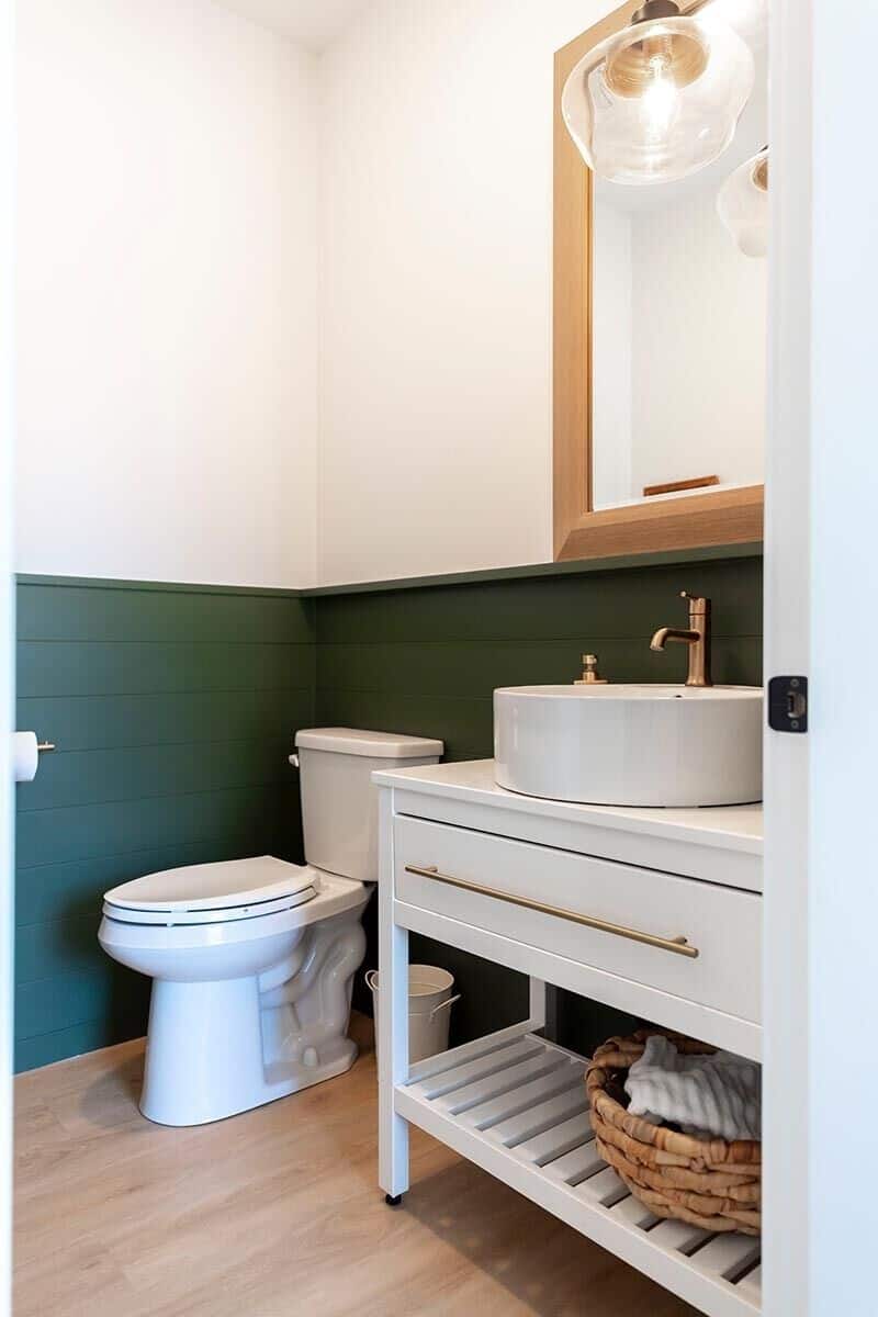 Green shiplap walls add a pop of color to the powder room.
