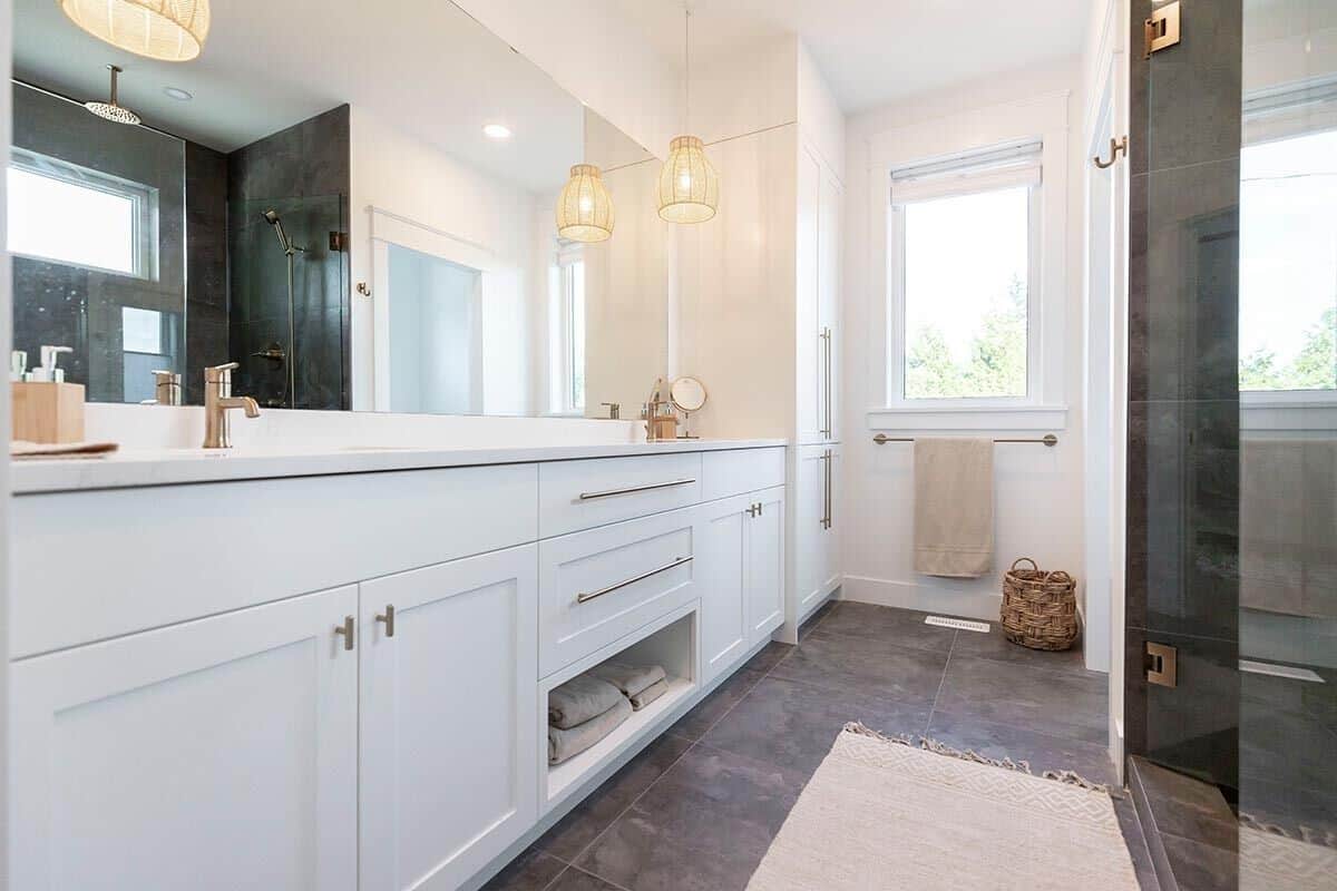 Primary bathroom with a dual sink vanity, a walk-in shower, and a picture window.