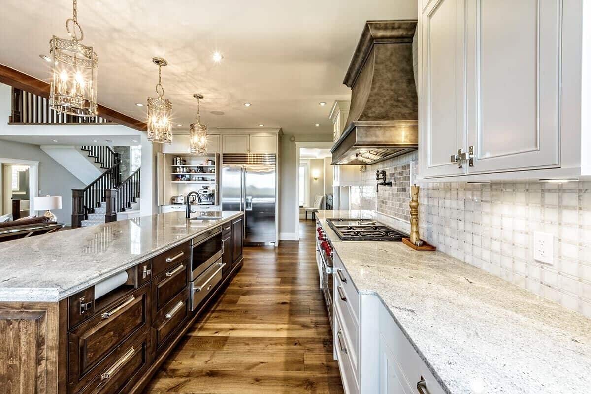 The kitchen offers top-of-the-line appliances, white cabinetry, and an immense island fitted with a prep sink.
