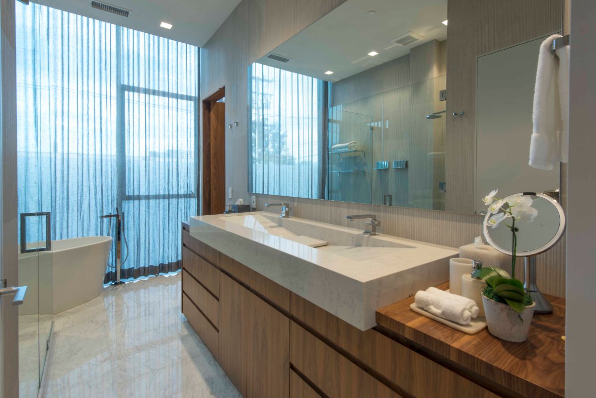 The bathroom has a freestanding tub, and a walk-in shower and a marble sink beneath a full-width mirror.