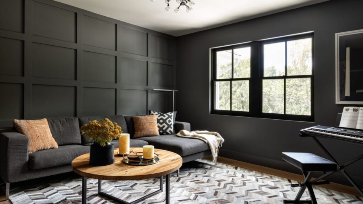 The office space has a small living area with a dark grey cushion and wooden coffee table that go well together.