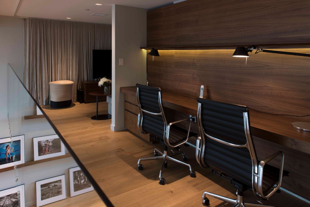 A second-floor home office with the same dark timber tone of the deck and the wall. The two trendy working chairs complemented the wood materials.