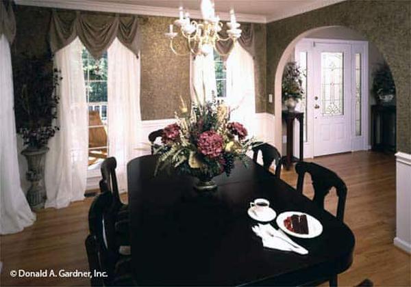 Formal dining room with an oval dining set and tall windows dressed in classy drapes and sheer curtains.