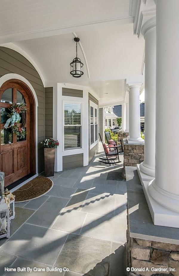The covered entry porch is filled with dark wood rocking chairs and various ornaments.