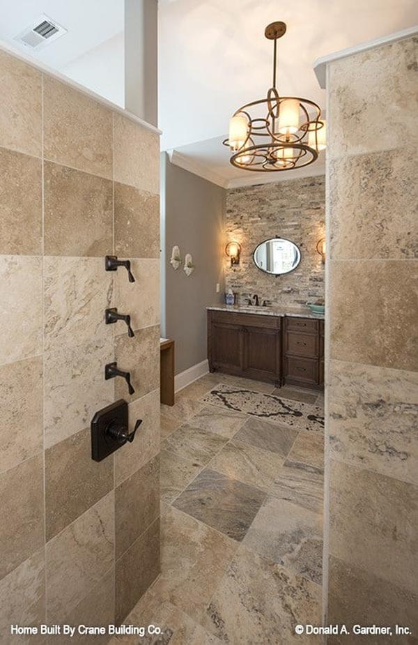 The walk-in shower has wrought iron fixtures and tiled walls that match the bathroom flooring.