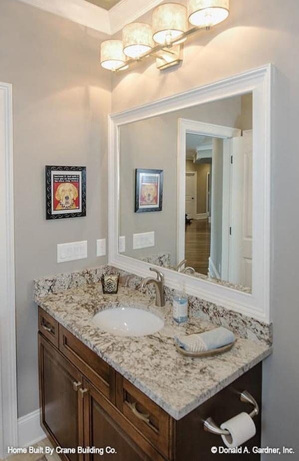 The bathroom features a wooden vanity paired with a large white framed mirror.