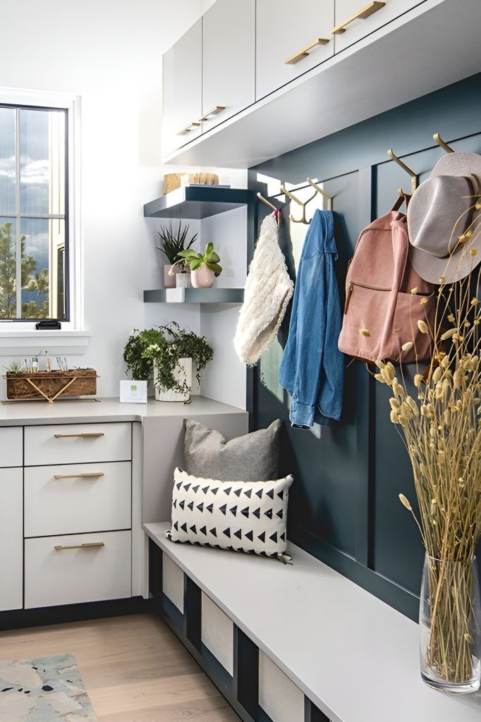The mudroom is filled with white cabinets, black shelves, hooks, and a built-in storage bench.