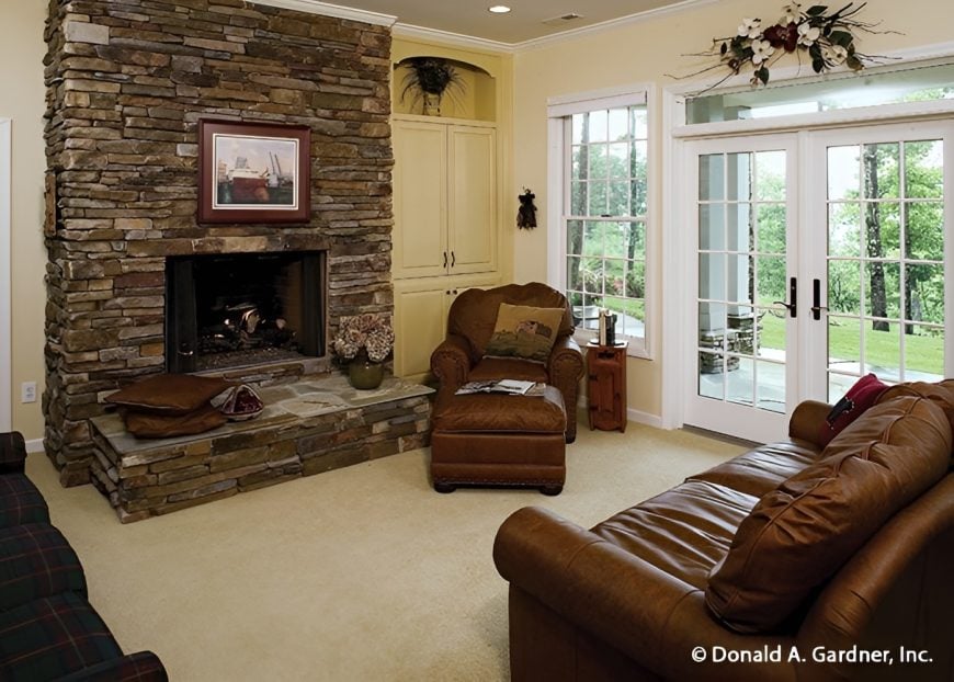 Recreation room with a stone fireplace, leather seats, and a french door leading to the covered patio.