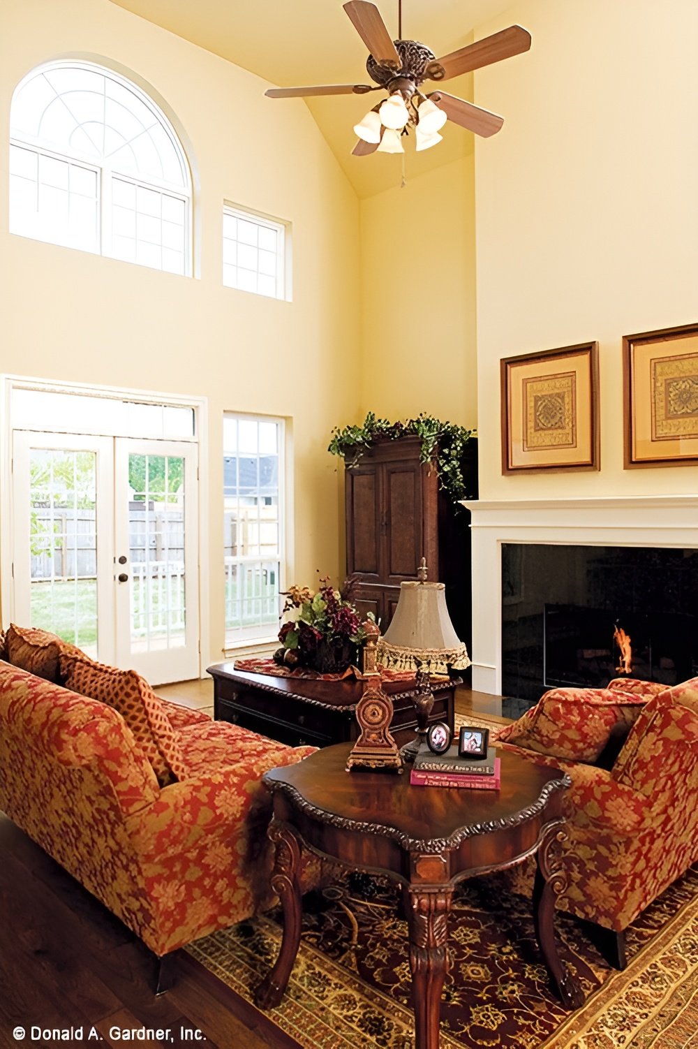 The great room includes a fireplace and a ceiling fan hanging from the two-story ceiling.