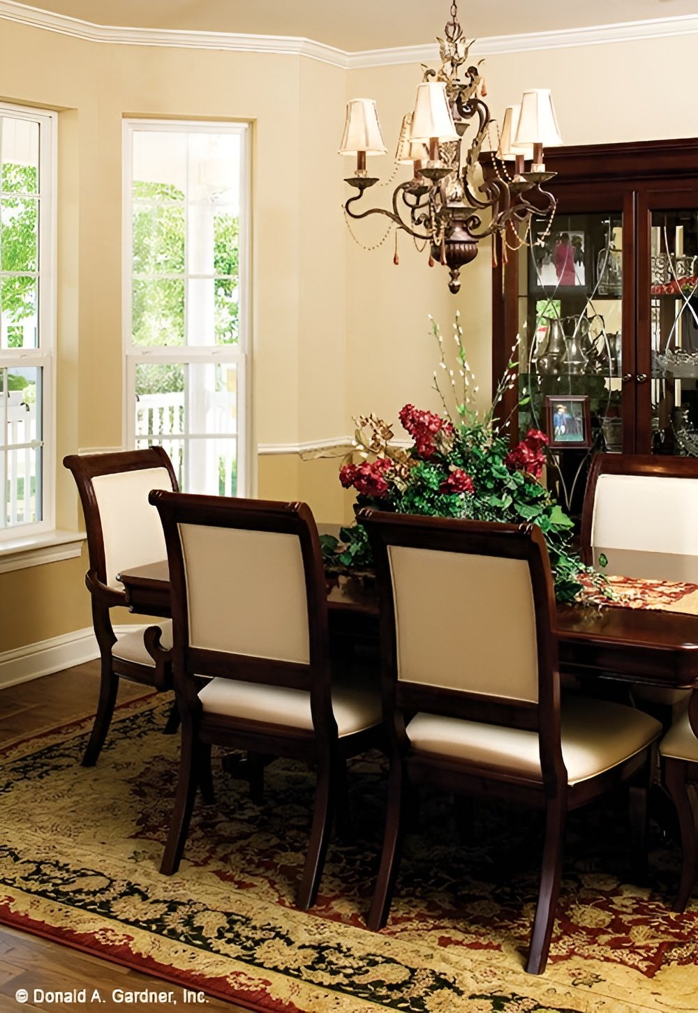 Dining room with a china cabinet and a matching dining set topped with an ornate chandelier.