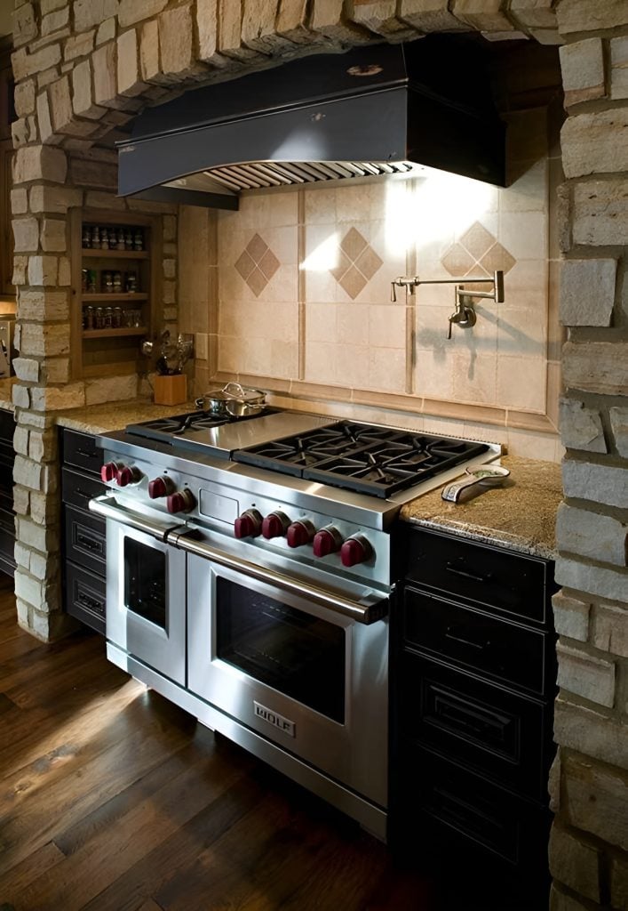 A closeup look at the cooking alcove adorned with marvelous stone bricks and decorative tile backsplash.
