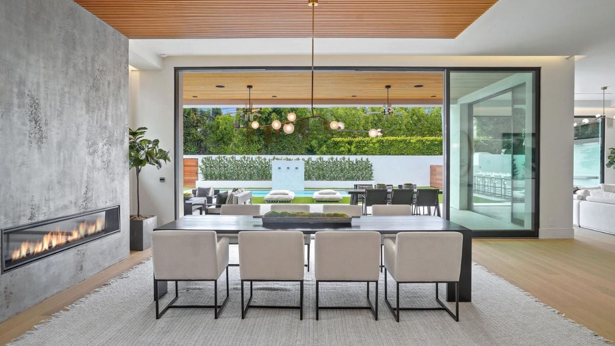 Full-height sliding glass doors extend the living space to the luxury pool, outdoor dining room, and patio seating.