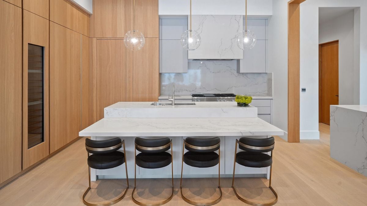 The kitchen showcases a front and clear view, accentuated by the elegant wood slat accents in the cabinets and luxurious marble adorning the walls and countertops.