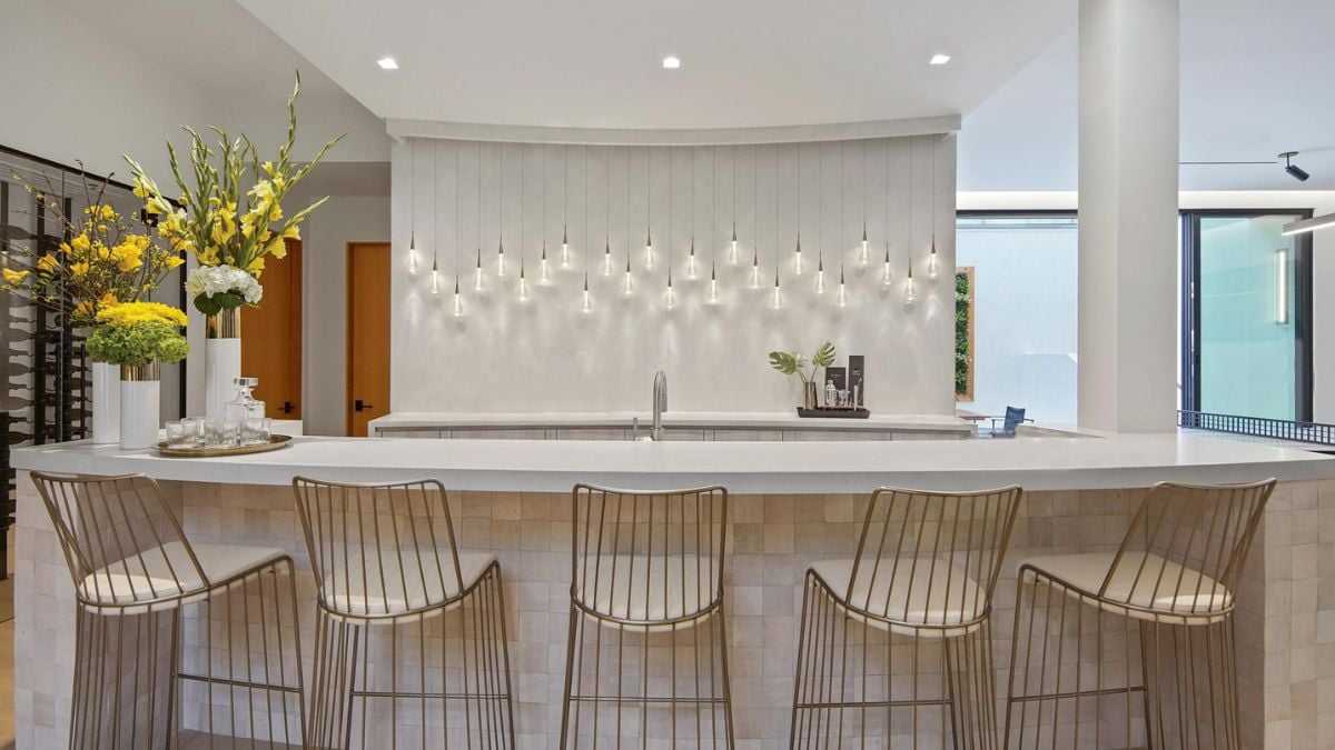 The home bar features a gracefully curved island adorned Zellige tiles, complemented by glass pendant lights along the back bar, while a built-in wine room ensures a plentiful supply of chilled bottles.
