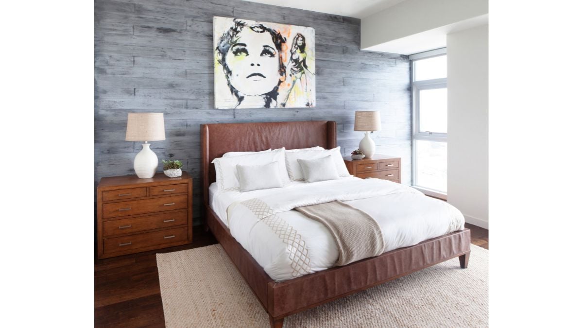 In this bedroom, the artwork is elegantly displayed on the wall directly above the head of the bed, complemented by two lamps positioned on either side.