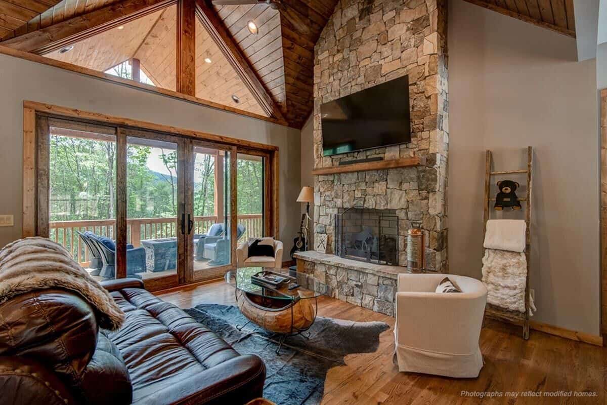 Living room with leather seats and a stone fireplace topped with a TV.