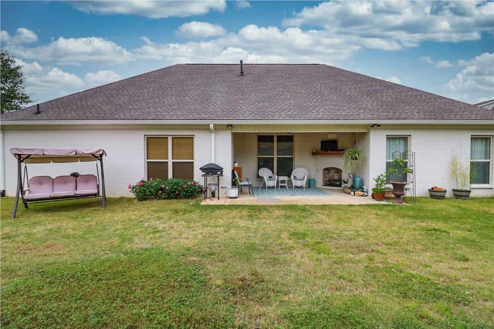 View of the house from the backyard showcasing its covered porch under a hipped roof.