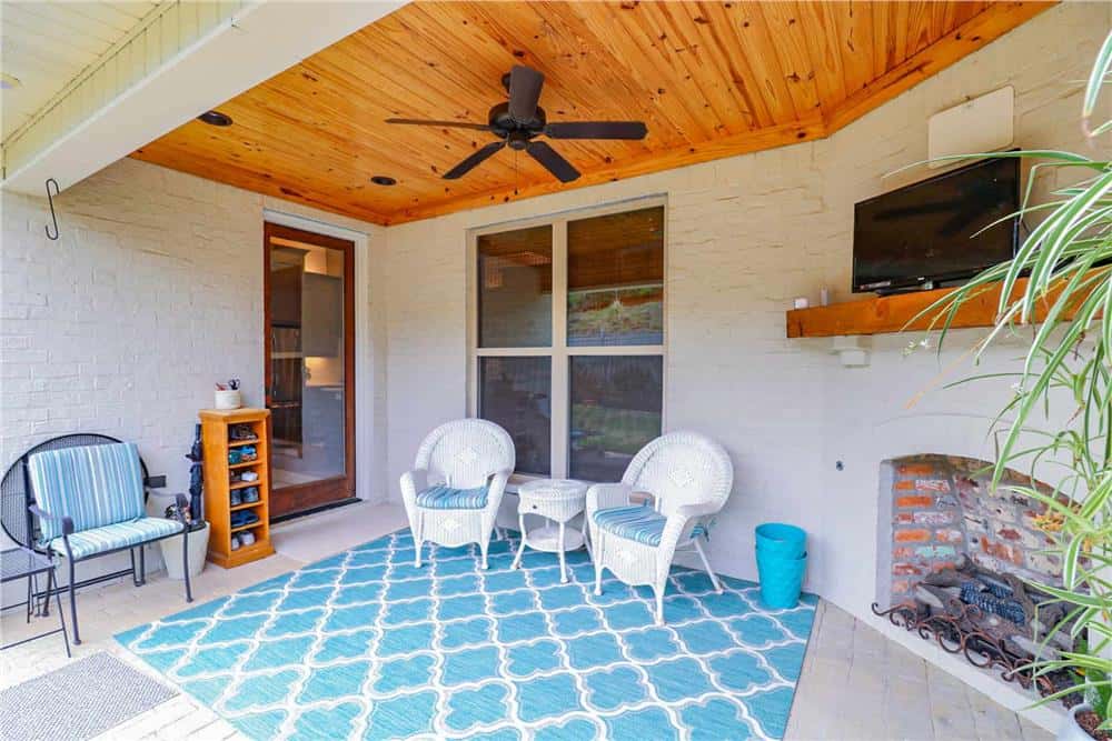 The covered porch offers a great space for entertaining complete with round-back armchairs and an outdoor fireplace.