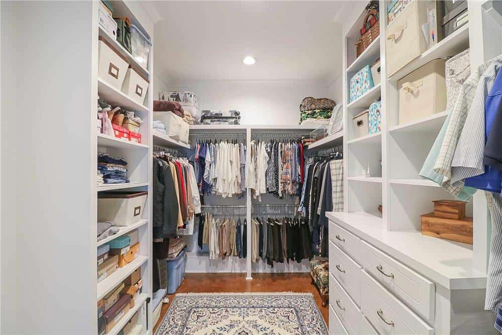 A walk-in closet filled with built-in shelves, drawers, and hanger rods.