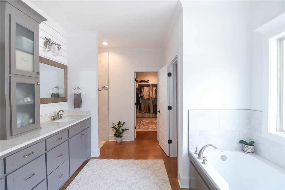 The primary bathroom offers a dual vanity sink, a drop-in bathtub, a tiled shower, and a walk-in closet.