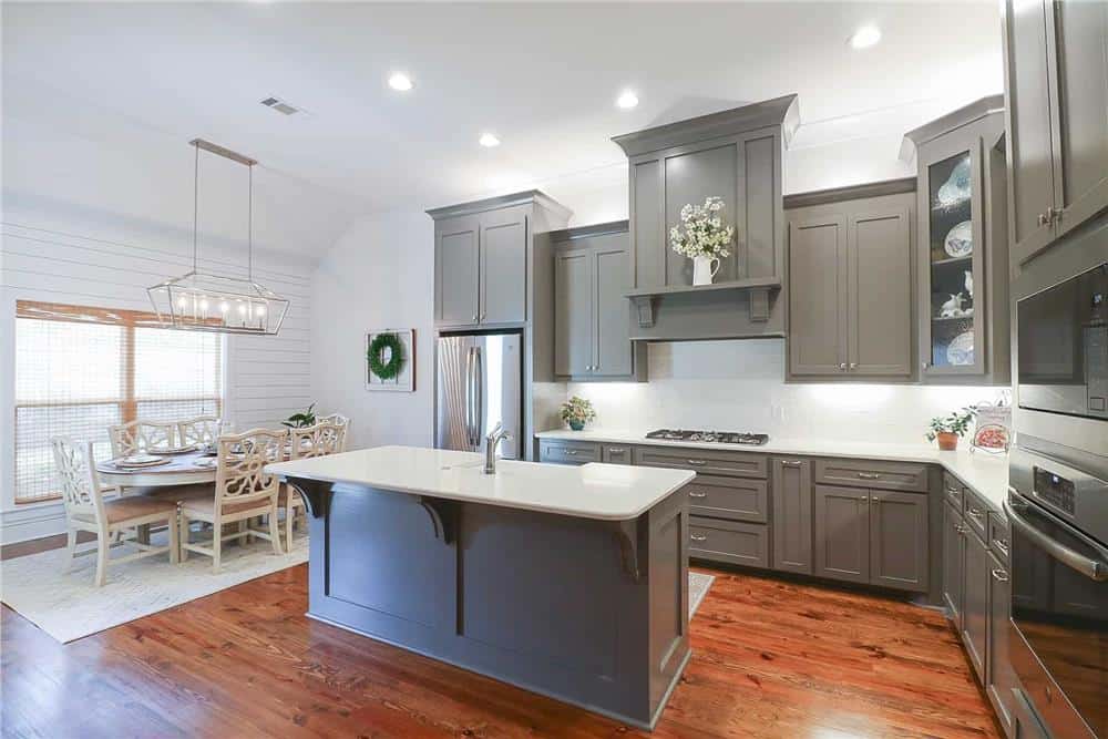Kitchen with gray cabinets, stainless steel appliances, and a breakfast island fitted with a prep sink.