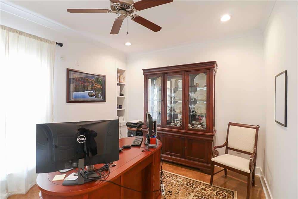 Home office with a display cabinet, an oval desk, and built-in shelves.