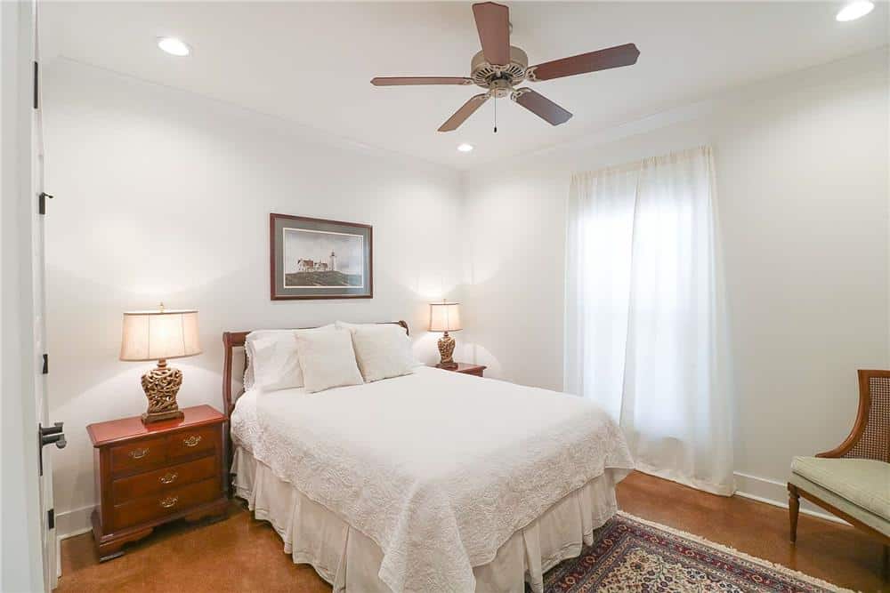 This bedroom features pristine white walls softened by natural wood furnishings and hardwood flooring.