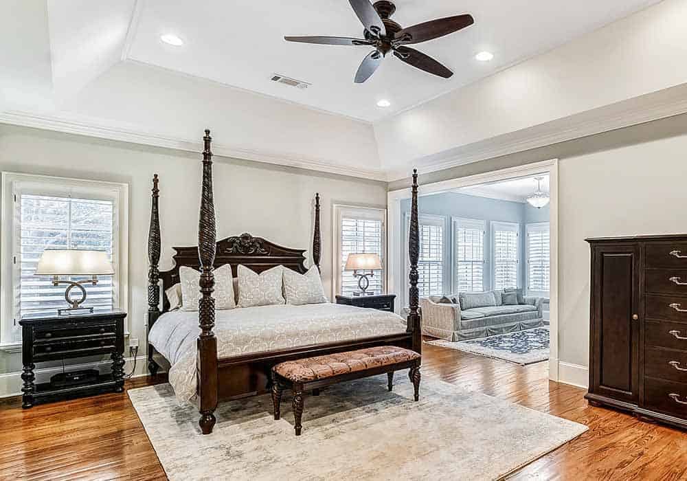 The primary bedroom features a tray ceiling, a four-poster bed, and an adjoining sitting room.