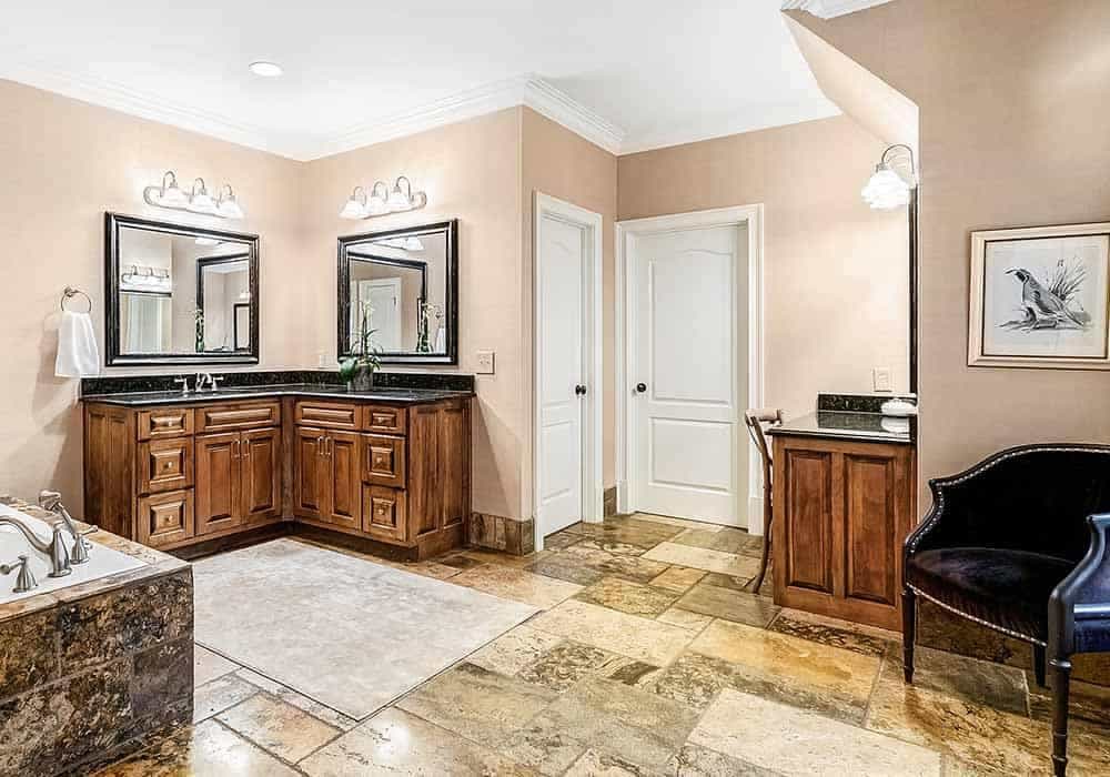 The primary bathroom offers a dual sink vanity over limestone flooring.