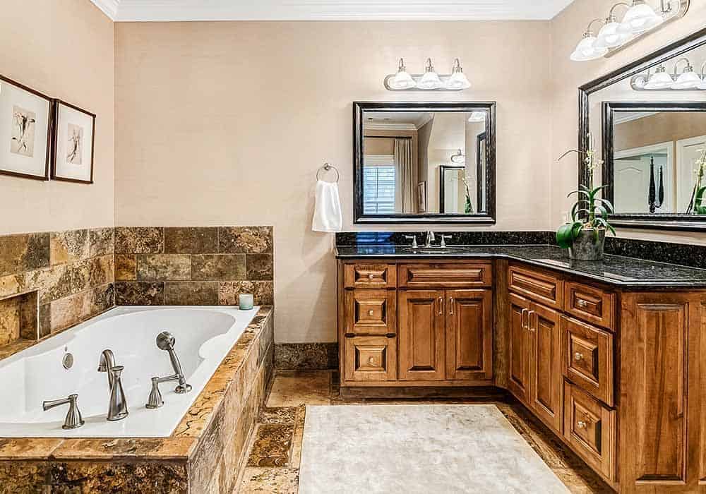 The primary bathroom includes a deep soaking tub fixed against the beige walls.