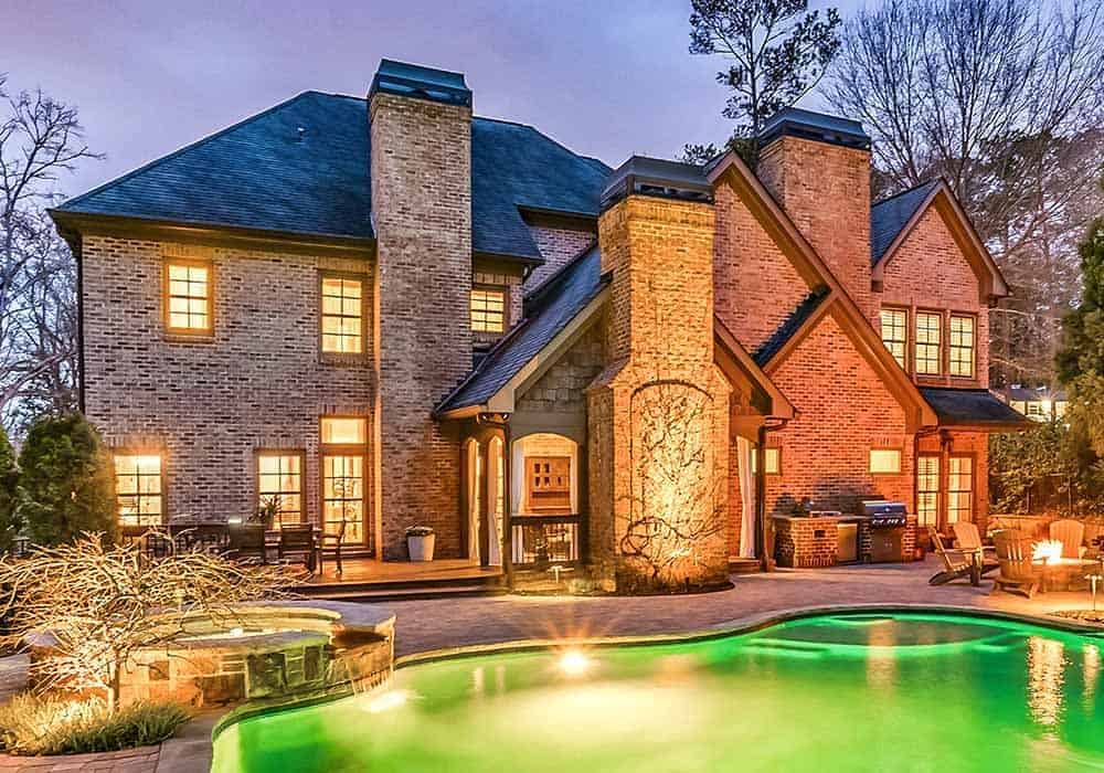 View of the house from the backyard showcasing its stately brick exterior, expansive outdoor living, and a pool terrace.