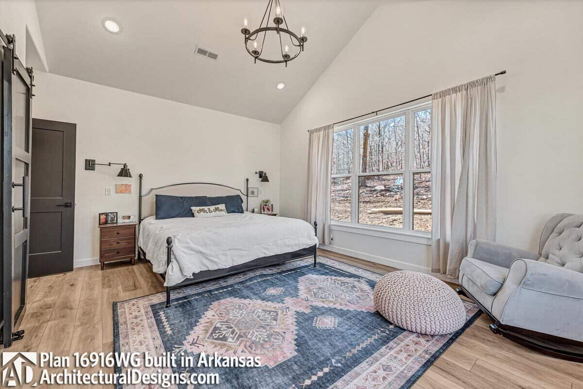 Primary bedroom with a vaulted ceiling and wide plank flooring topped by a large area rug.