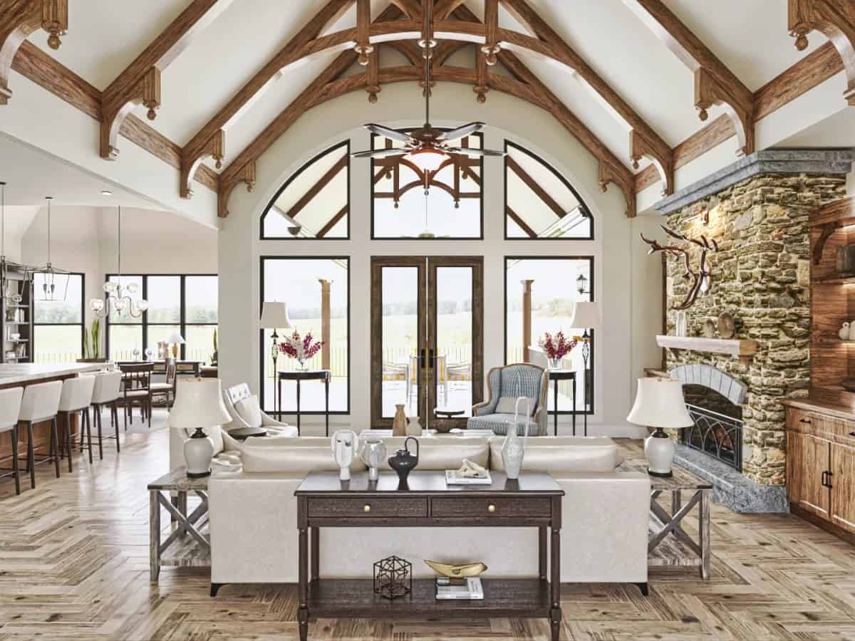 Great room with a large stone fireplace, leather sofas, and a cathedral ceiling framed with exposed trusses.
