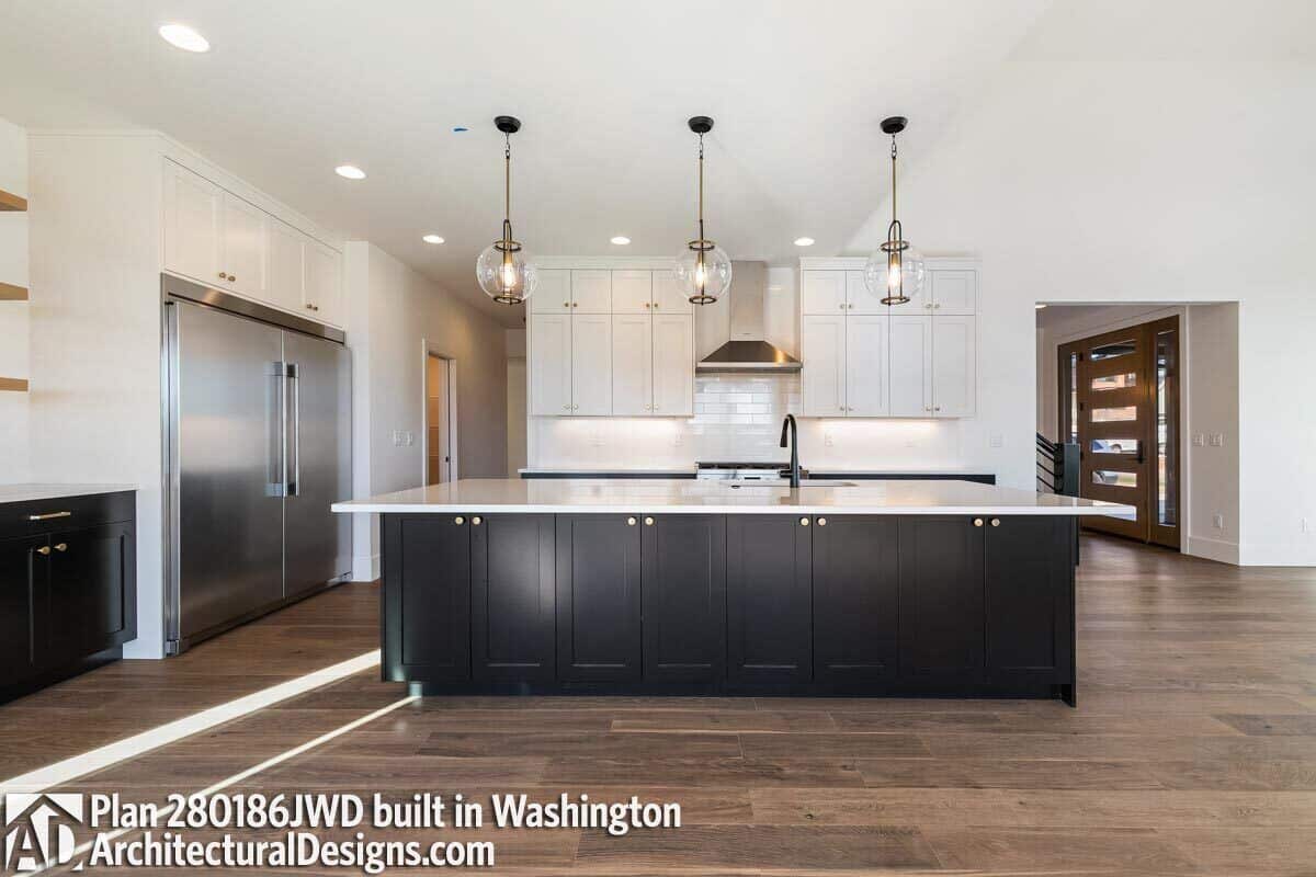 The kitchen features contrasting cabinets, premium appliances, and a large island topped with glass globe pendants.