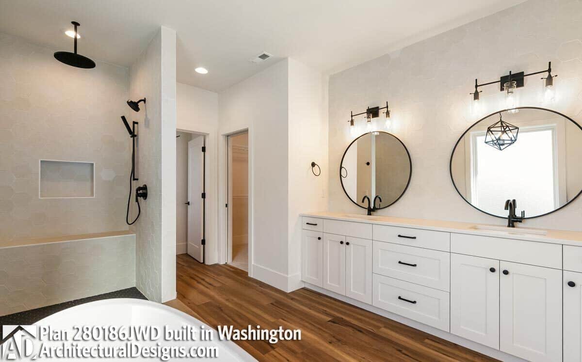 Primary bathroom with a tiled shower, a soaking tub, and a dual sink vanity paired with round mirrors.