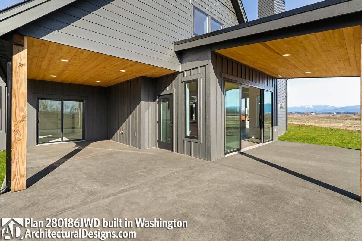 Wraparound patio with concrete flooring and wood-paneled ceilings.