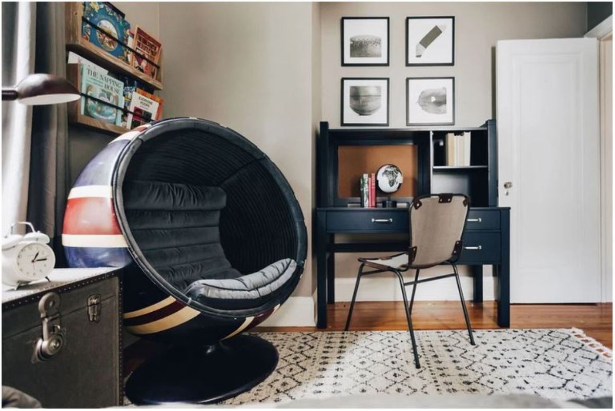 A orbital chair and a black study table with four frames above in a carpeted floor.