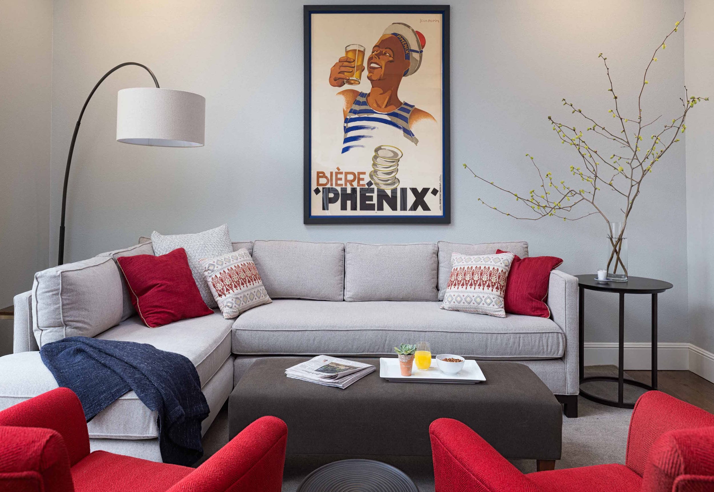 Center view of the living room, featuring the art piece against the wall and the beautiful sofas with sofa pillows, and a small table with a vase.