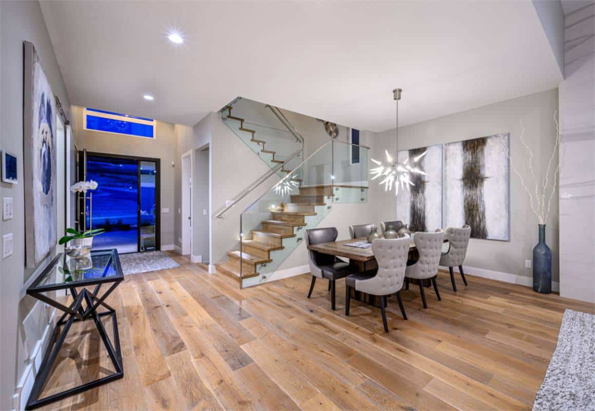 The dining area illuminated by a sputnik chandelier sits against the modern staircase.