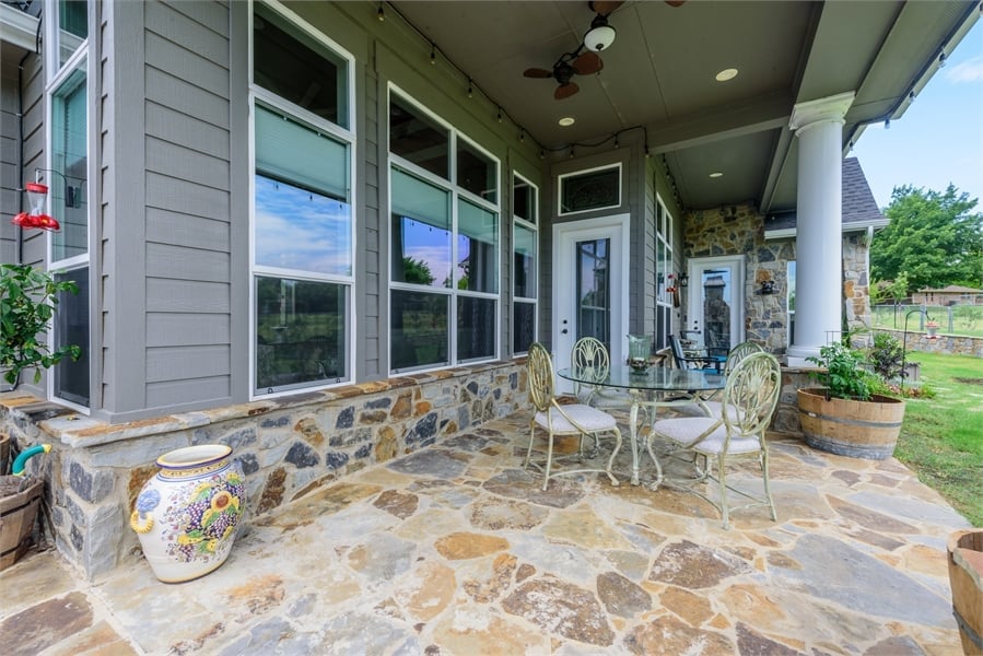 Covered porch with a round dining set over flagstone flooring.