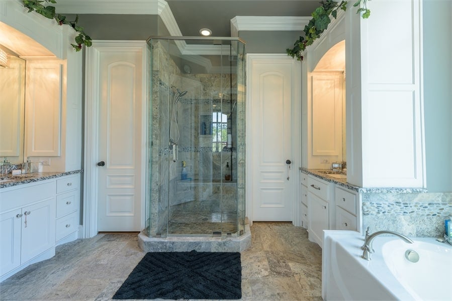 The primary bathroom offers his and her sink vanities, a tiled shower, and a soaking tub.