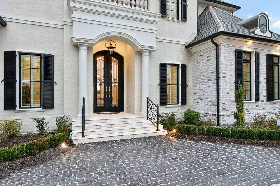A closer look at the home's entry with a tiled stoop, round columns, and an arched French door.