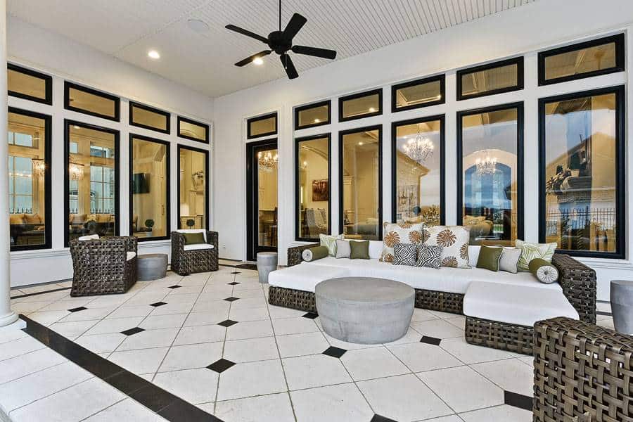 The covered porch has cushioned wicker seats and walls of windows that blur the line between indoor and outdoor living.