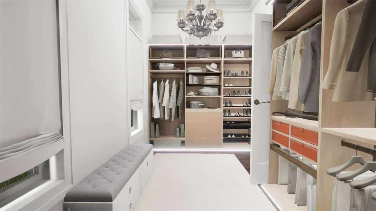 The primary walk-in closet is bright and spacious. It offers lots of storage space and a tufted bench.
